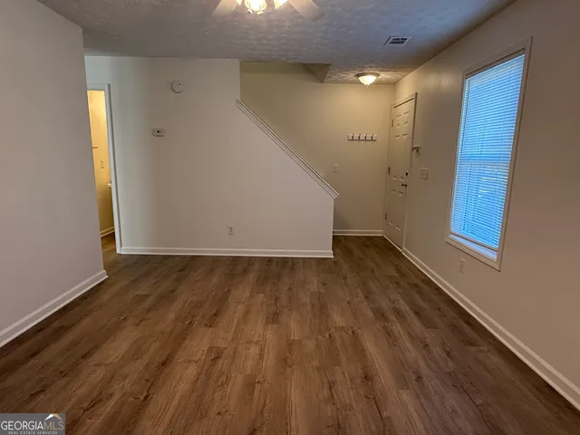 an empty room with wooden floor fan and windows