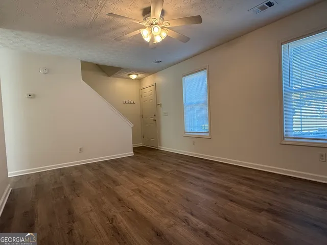 a view of an empty room with window and wooden floor