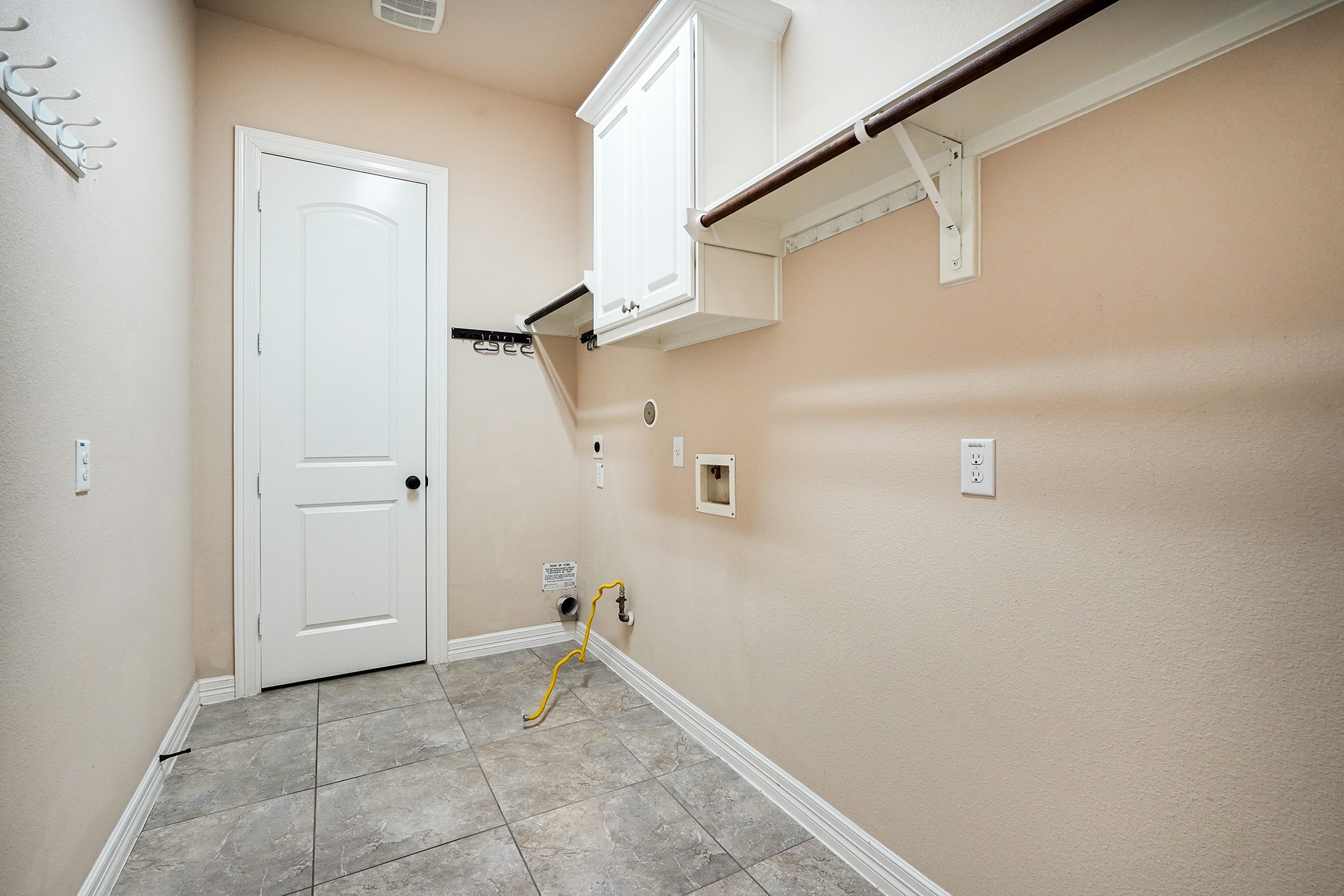 3102 Barrons Way Sugar Land, TX 77479 - Photo 20 of 42 This is a spacious laundry room with tiled flooring, a white door, wall-mounted cabinets, and connections for a washer and dryer. It features ample shelving for storage.