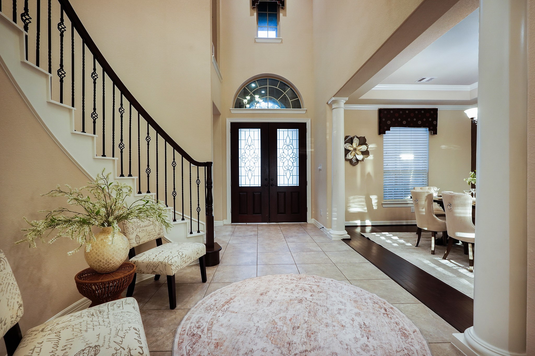3102 Barrons Way Sugar Land, TX 77479 - Photo 21 of 42 The elegant foyer features a grand curved staircase with wrought iron railings, a stylish tiled floor, and a high ceiling with arched windows. The entryway flows into a spacious dining area with classic columns, offering a welcoming and sophisticated first impression.