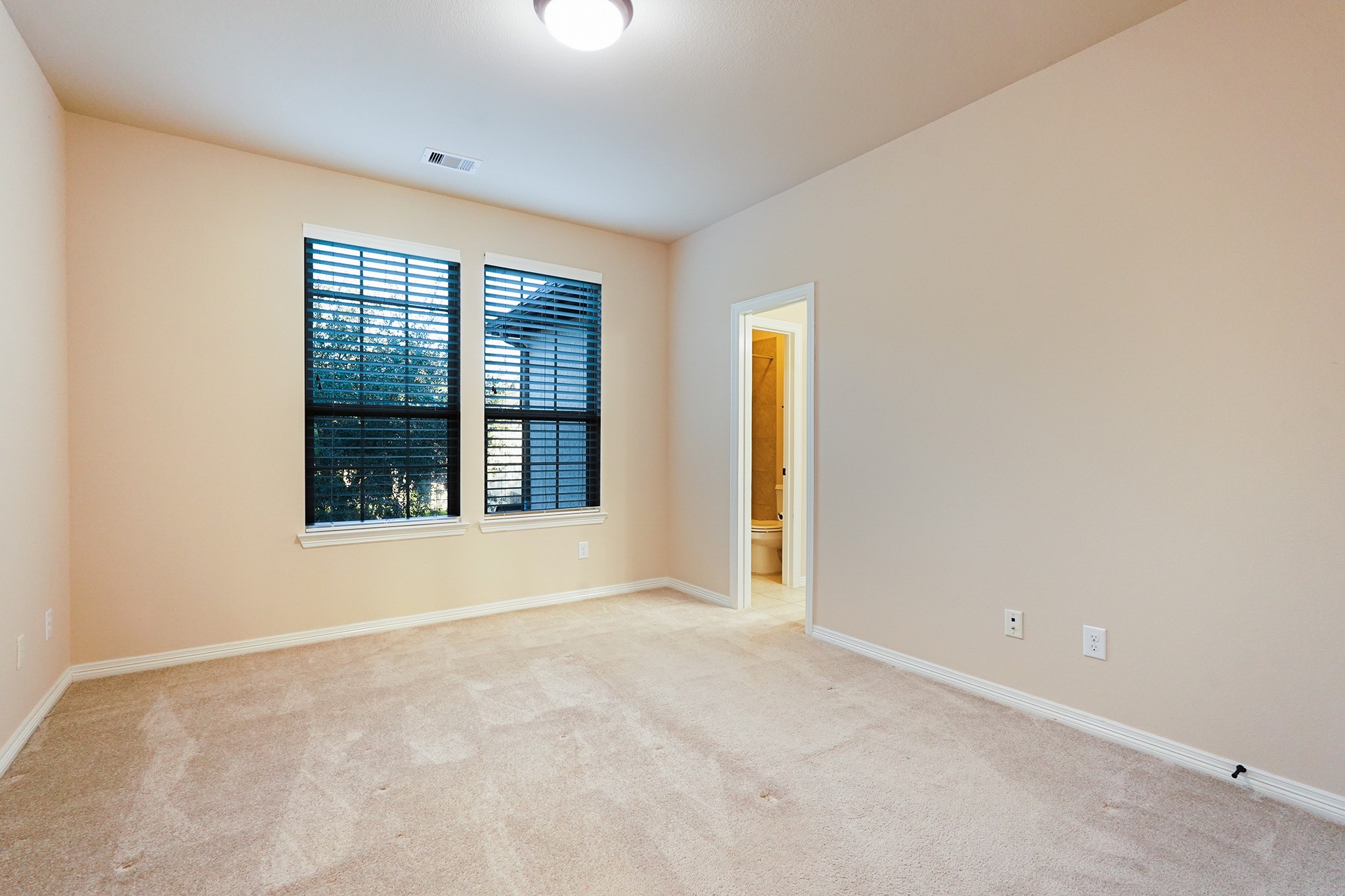 3102 Barrons Way Sugar Land, TX 77479 - Photo 23 of 42 SECOND Flr-Bed#3: This is a bright, cozy bedroom with neutral walls and carpet. It features two large windows with blinds and an en-suite bathroom. Perfect for a peaceful retreat.