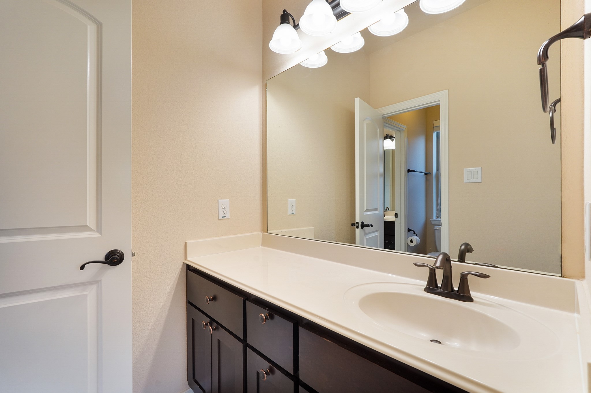 3102 Barrons Way Sugar Land, TX 77479 - Photo 28 of 42 SECOND Flr-Bath#4: This bathroom features a modern, clean design with a large mirror, ample countertop space, and dark wood cabinetry. The light fixtures add brightness, and there's a stylish sink with a sleek faucet.