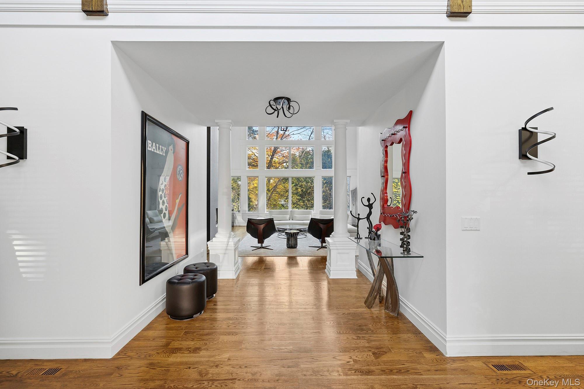 144 Round Swamp Road West Hills, NY 11743 - Photo 13 of 39 Hallway featuring decorative columns, wood finished floors, and expansive windows