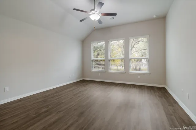 an empty room with wooden floor chandelier fan and windows