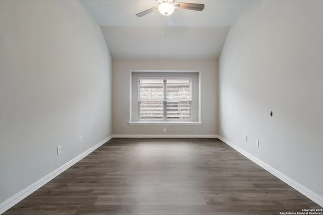a view of an empty room with a window and wooden floor