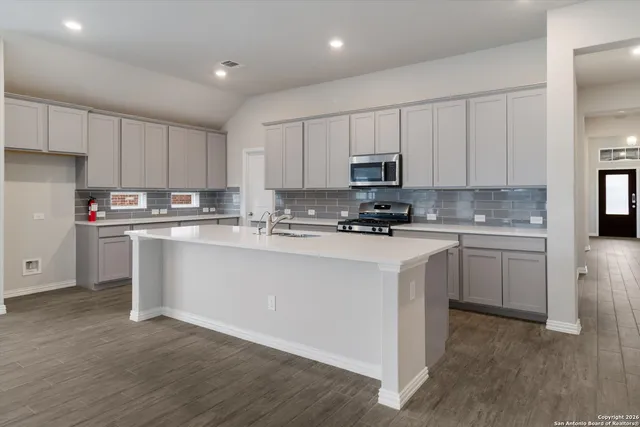 a kitchen with stainless steel appliances white cabinets a sink a stove a microwave and wooden floors