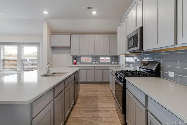 a kitchen with a sink stove top oven and cabinets