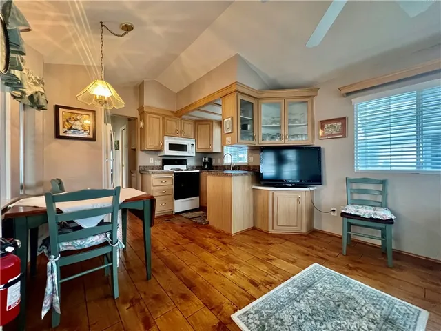 a kitchen with stainless steel appliances granite countertop a stove a sink dishwasher a dining table and chair with the wooden floor