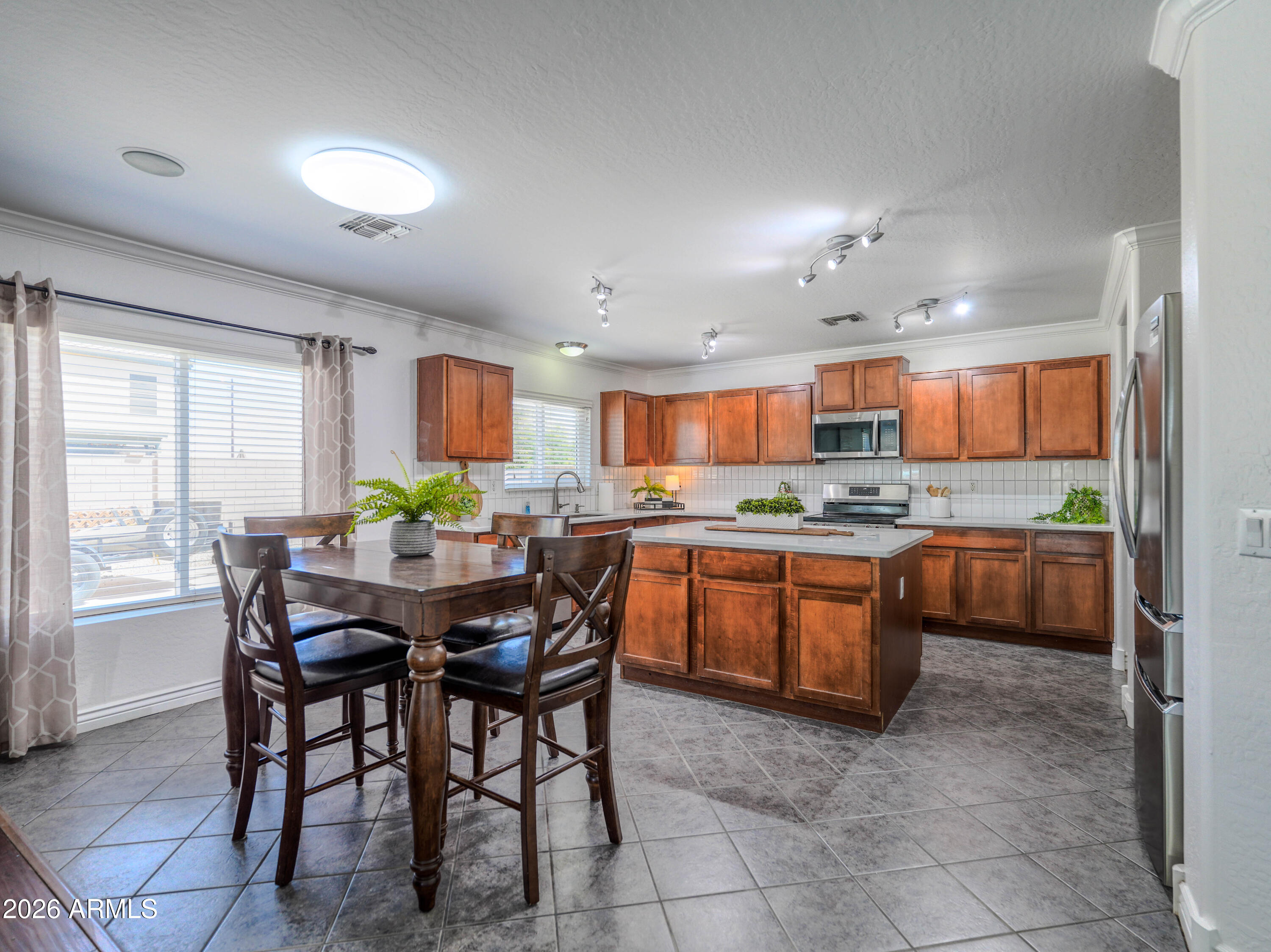 3378 East Silverbell Road San Tan Valley, AZ 85143 - Photo 18 of 61 a kitchen with stainless steel appliances granite countertop a table chairs and a refrigerator