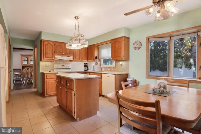 a kitchen with kitchen island granite countertop a stove top oven a sink a counter top space and cabinets