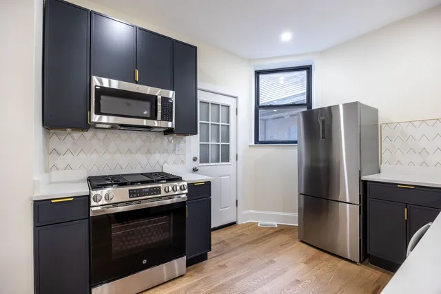 a kitchen with stainless steel appliances granite countertop a refrigerator a sink a stove and wooden floors