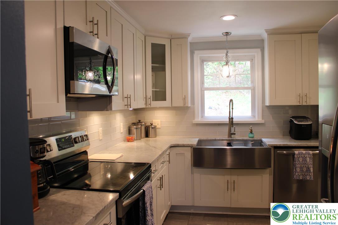 635 Silver Spring Boulevard Kunkletown, PA 18058 - Photo 14 of 34 a kitchen with stainless steel appliances a sink a stove a microwave a sink and cabinets