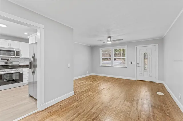 a view of an empty room with a window and wooden floor