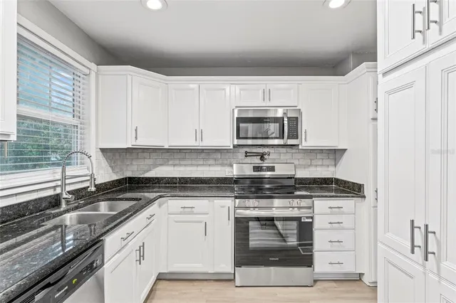 a kitchen with cabinets stainless steel appliances and a window