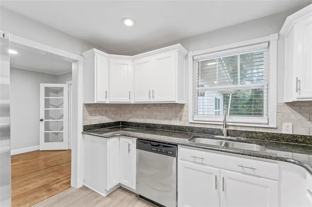 a kitchen with granite countertop white cabinets and a window