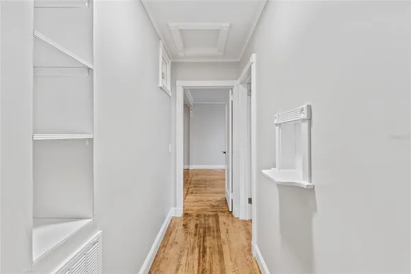 a view of a hallway with wooden floor and a bathroom