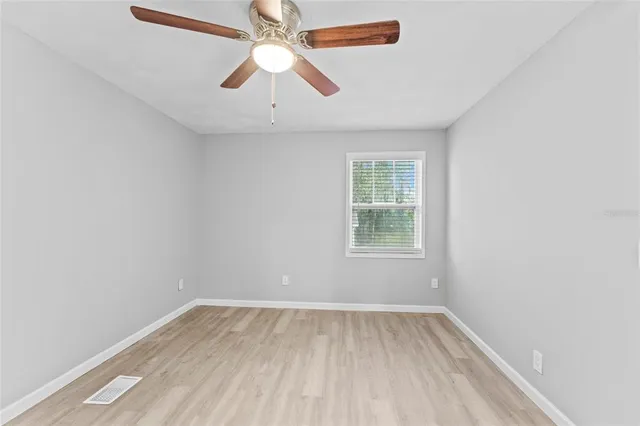 an empty room with a window and a fan