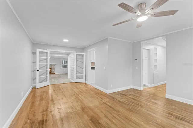 a view of empty room with wooden floor and fan