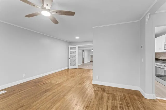 a view of an empty room with wooden floor closet and a window