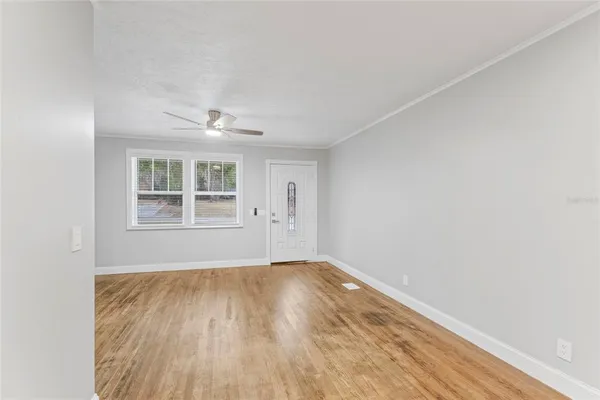 a view of an empty room with wooden floor and a window