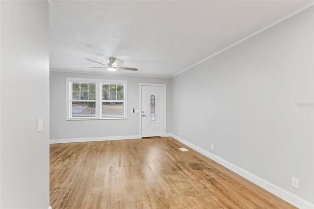 a view of an empty room with wooden floor and a window