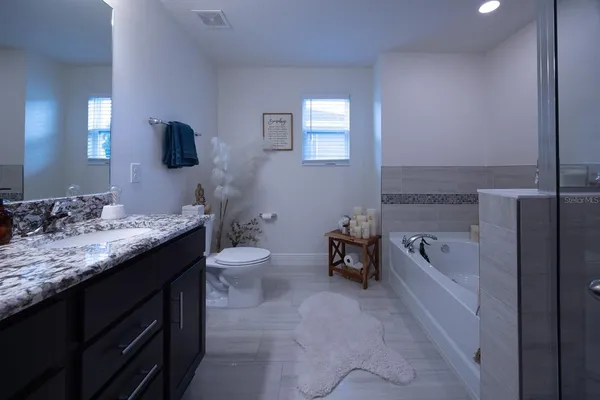 a bathroom with a granite countertop sink a toilet and bathtub