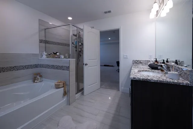 a spacious bathroom with a granite countertop sink mirror and bathtub