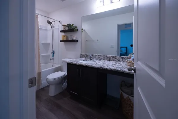 a bathroom with a granite countertop sink toilet and mirror