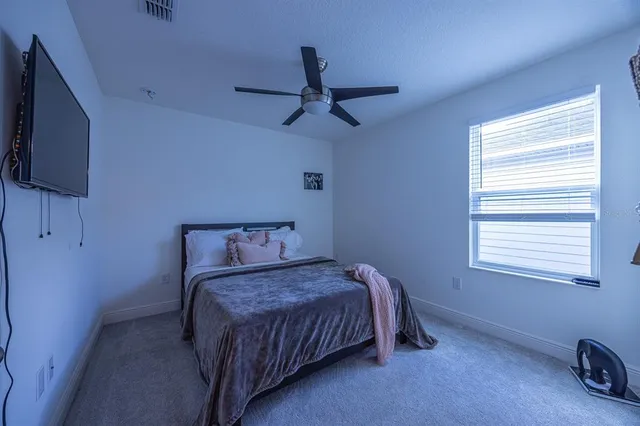 a bedroom with a bed next to a window with a flat screen tv