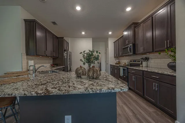 a kitchen with kitchen island granite countertop stainless steel appliances sink stove microwave and cabinets