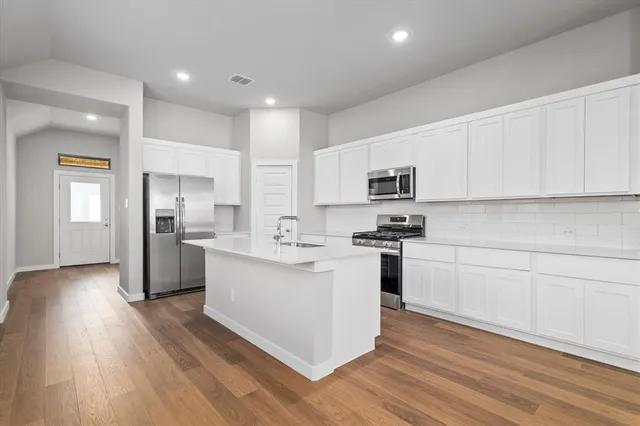 a kitchen with stainless steel appliances white cabinets and wooden floor