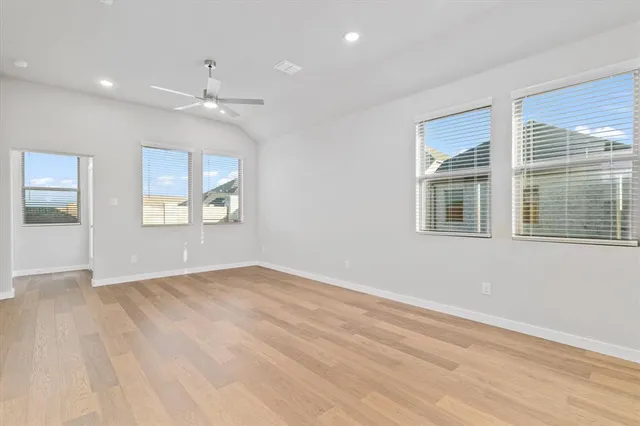 an empty room with wooden floor chandelier and windows