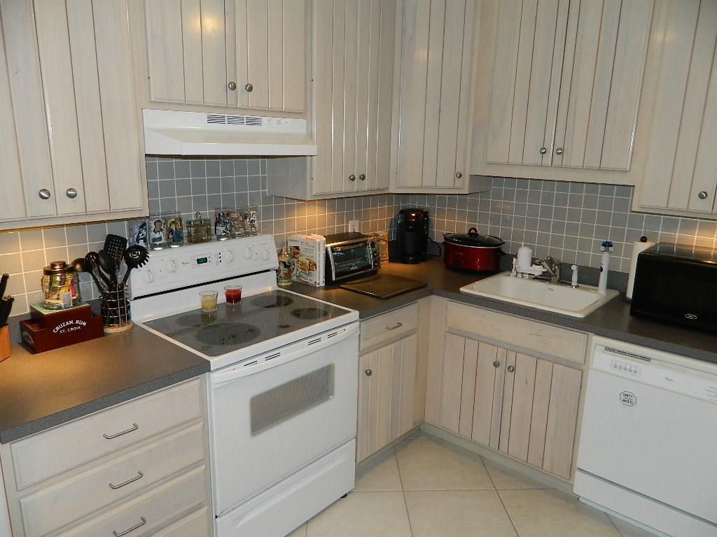390 Golfview Road, Unit B North Palm Beach, FL 33408 - Photo 2 of 22 a kitchen with white cabinets and white appliances