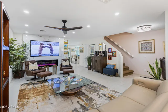 a living room with furniture a flat screen tv and floor to ceiling window
