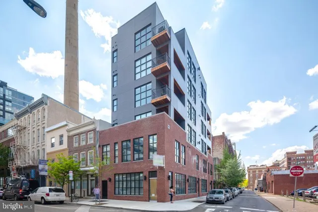 a front view of a building with lot of cars and trees