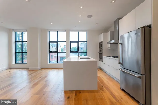 a kitchen with stainless steel appliances a refrigerator and wooden floor
