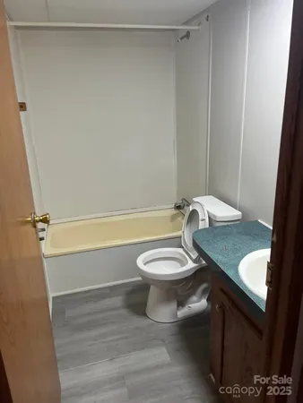 a bathroom with a granite countertop bathtub shower sink vanity and toilet