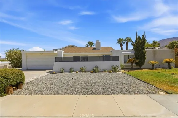 a front view of a house with a yard and mountain view in back