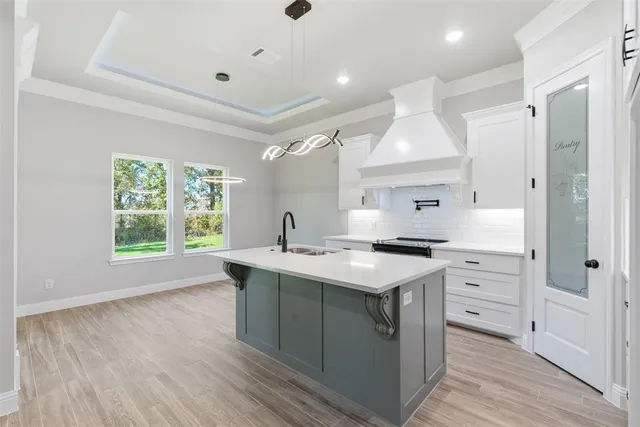 a kitchen with a stove a sink and wooden floor