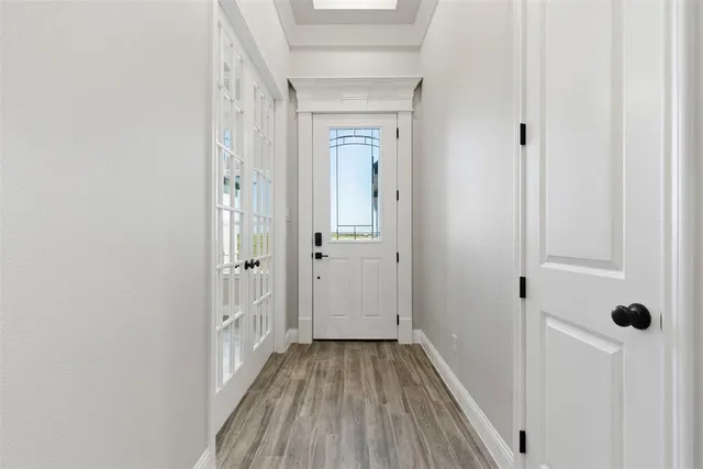 a view of a hallway with wooden floor and a bathroom