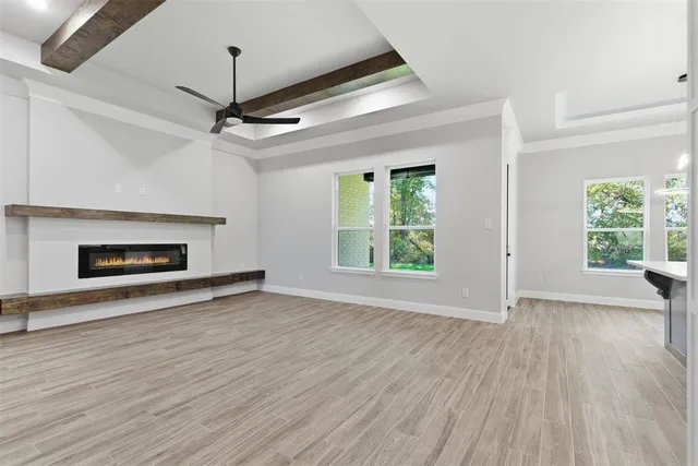 an empty room with wooden floor fireplace and windows