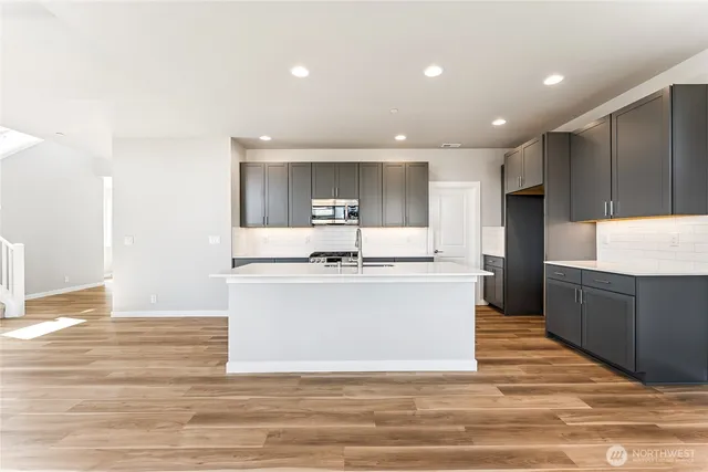a large kitchen with kitchen island a sink wooden floor and stainless steel appliances