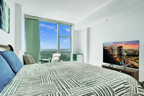 a bedroom with a bed a computer on the desk and a rug