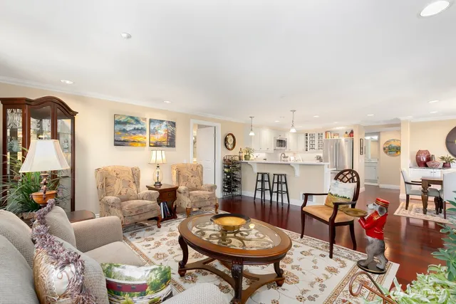 a kitchen with stainless steel appliances kitchen island granite countertop a stove top oven a sink a dining table and chairs with wooden floor