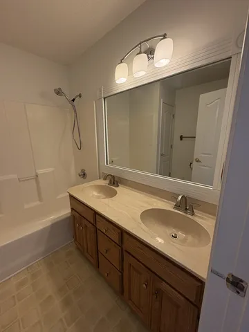 a bathroom with a double vanity sink mirror double and bathtub