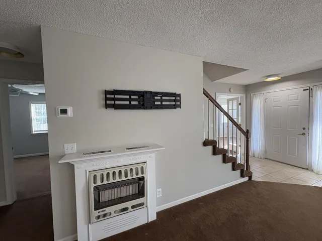 a view of an empty room with stairs fire place and a kitchen view