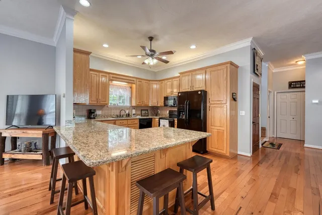 a large kitchen with granite countertop a refrigerator a stove a sink a dining table and chairs