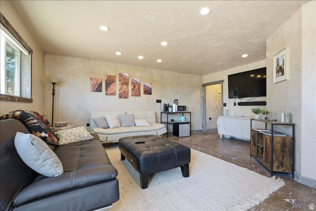 1634 West Arimo Road Arimo, ID 83214 - Photo 36 of 89 Spacious living area featuring recessed lighting, a window with wood trim, textured walls, concrete flooring, and an open doorway