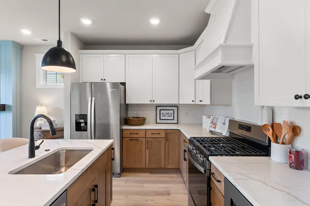 a kitchen with kitchen island stainless steel appliances a sink a stove and a refrigerator