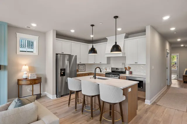 a kitchen with kitchen island a stove a sink a refrigerator and chairs